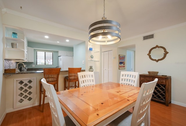 dining area with a chandelier, sink, dark hardwood / wood-style floors, and crown molding