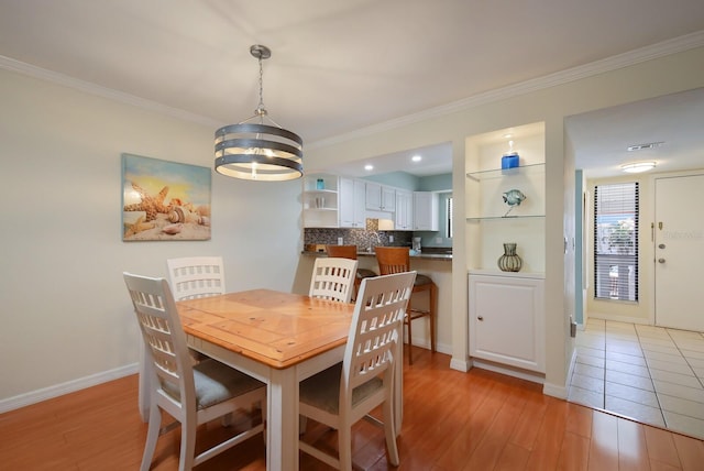 dining space with an inviting chandelier, light hardwood / wood-style floors, and crown molding