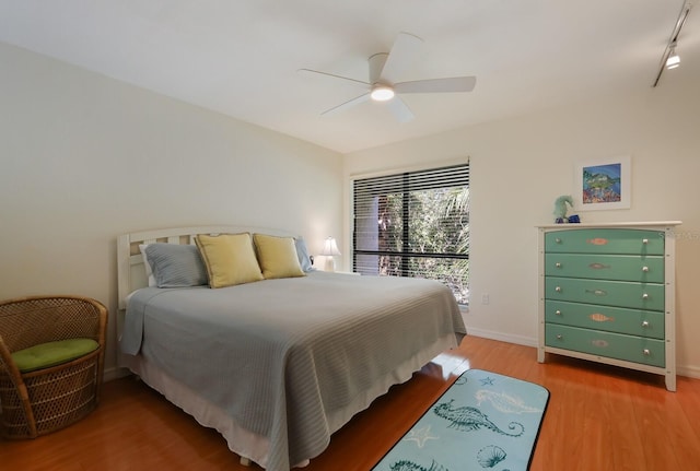 bedroom with hardwood / wood-style floors, ceiling fan, and rail lighting