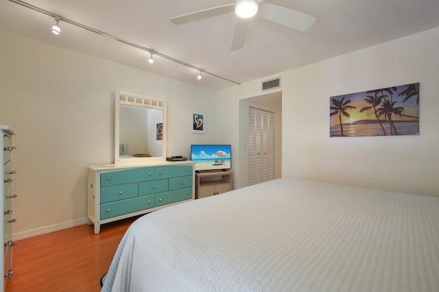 bedroom featuring a closet, ceiling fan, dark wood-type flooring, and track lighting