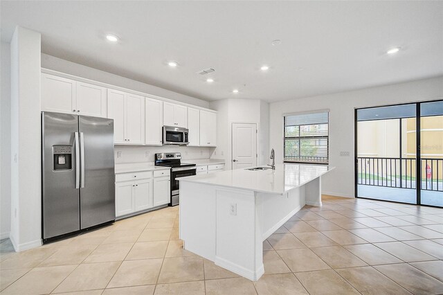 kitchen with a center island with sink, white cabinets, sink, light tile patterned flooring, and stainless steel appliances