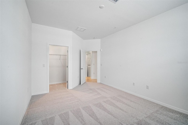 unfurnished bedroom with a spacious closet, light carpet, and a closet