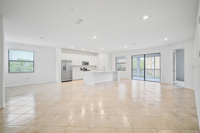 unfurnished living room with light tile patterned floors, a wealth of natural light, and sink