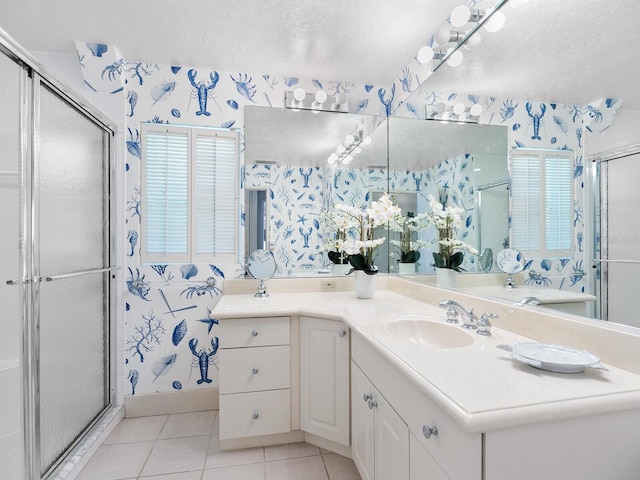 bathroom with a textured ceiling, vanity, tile patterned floors, and an enclosed shower