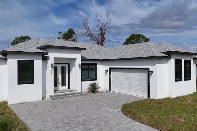 view of front of house with a shingled roof, decorative driveway, an attached garage, and stucco siding