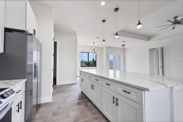 kitchen with white cabinets, stainless steel fridge with ice dispenser, light wood-style flooring, light stone countertops, and pendant lighting