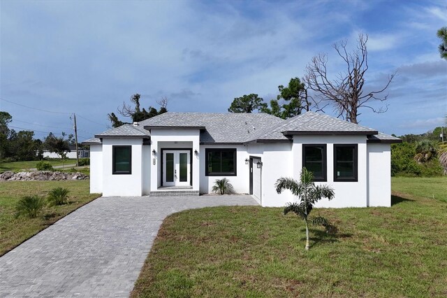 view of front of house featuring french doors, decorative driveway, a front yard, and stucco siding