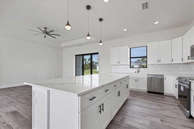 kitchen with white cabinetry, stainless steel appliances, and light stone counters