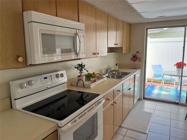 kitchen with sink, white appliances, light tile flooring, and plenty of natural light