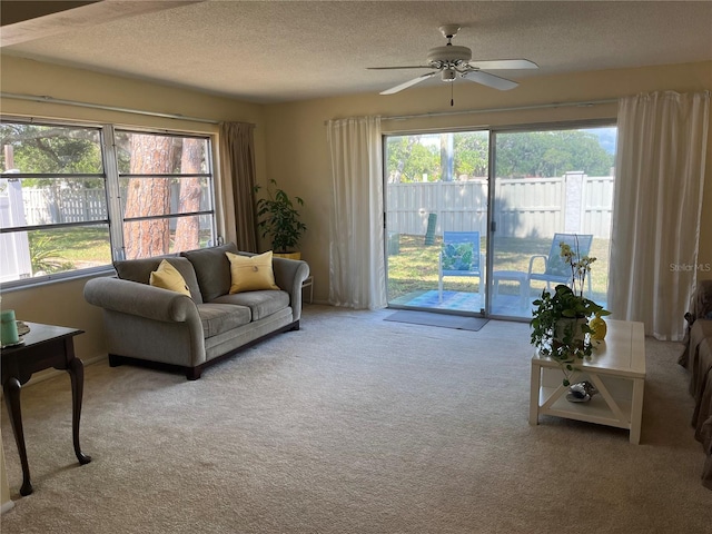 living room with a textured ceiling, ceiling fan, and carpet flooring