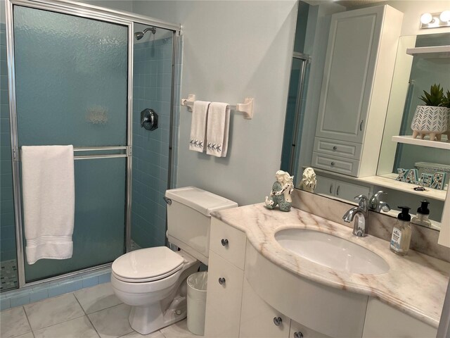 bathroom featuring tile flooring, vanity, toilet, and a shower with shower door