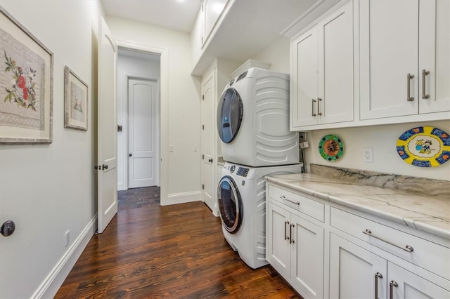 clothes washing area with stacked washing maching and dryer, cabinets, and dark hardwood / wood-style flooring