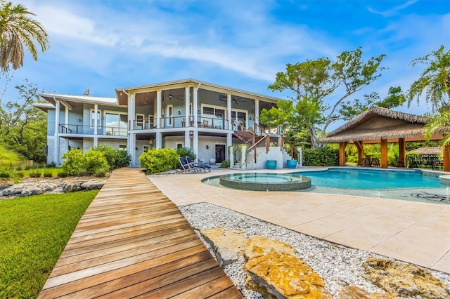 back of property with a balcony, a pool with hot tub, a gazebo, and a patio area