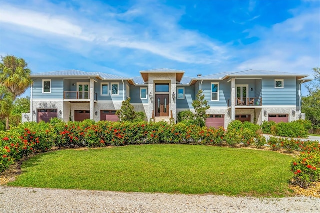 view of front of house featuring a balcony, a front lawn, and a garage