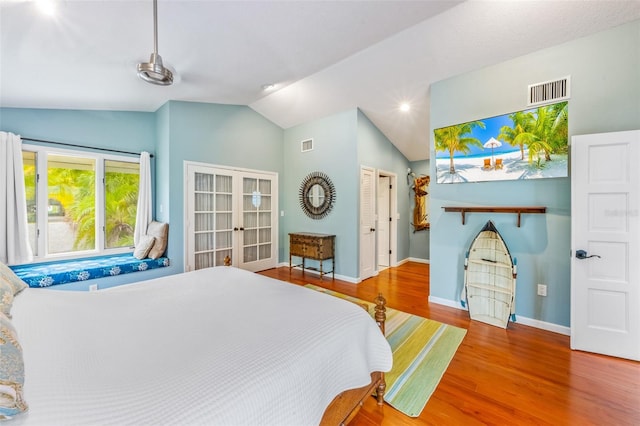 bedroom with hardwood / wood-style floors, lofted ceiling, and french doors