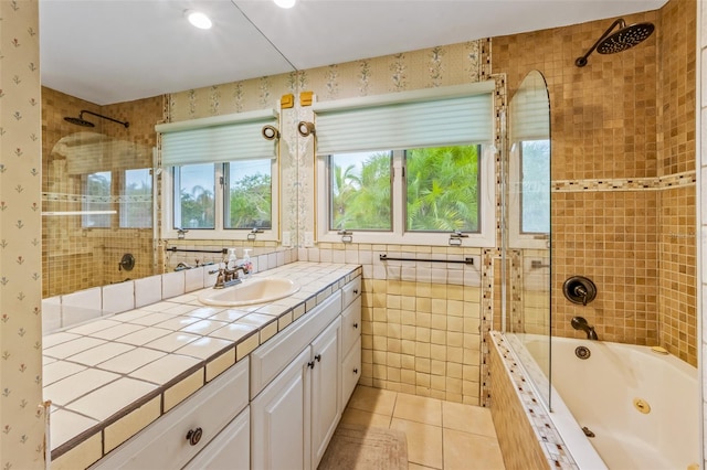 bathroom featuring tile walls, tile flooring, tiled shower / bath combo, and vanity