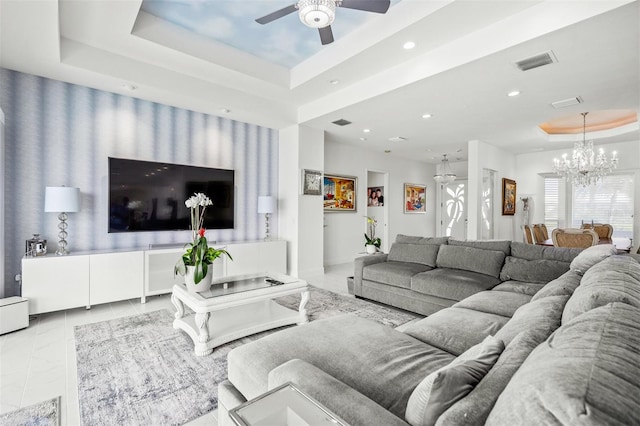 tiled living room featuring a raised ceiling and ceiling fan with notable chandelier