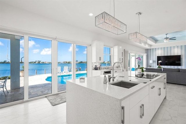 kitchen with white cabinets, decorative light fixtures, ceiling fan, and sink