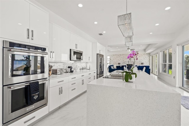 kitchen featuring light tile floors, ceiling fan, appliances with stainless steel finishes, white cabinetry, and hanging light fixtures