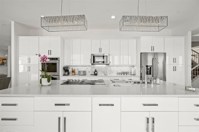 kitchen with stainless steel appliances, white cabinetry, and light stone counters