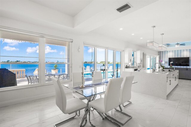 tiled dining area featuring a water view, ceiling fan, and sink