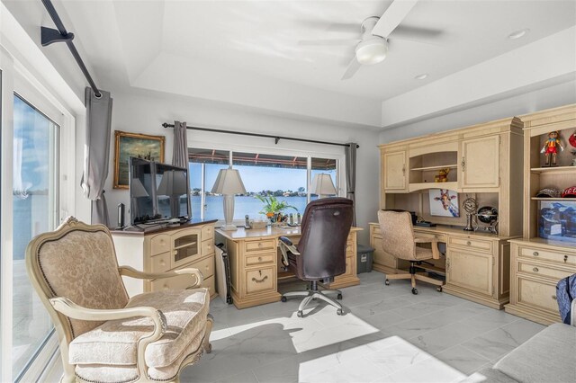 home office with plenty of natural light, a tray ceiling, ceiling fan, and light tile floors