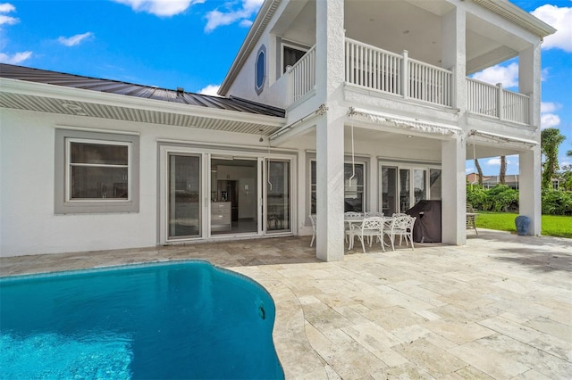 rear view of property featuring a balcony, a patio area, and french doors