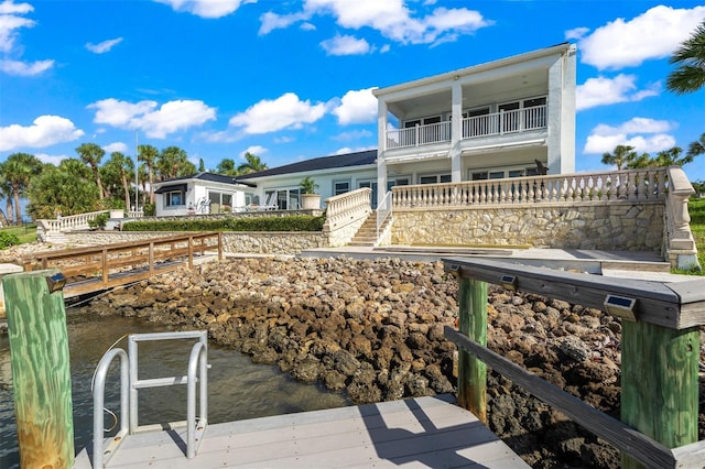 back of property with a balcony and a water view