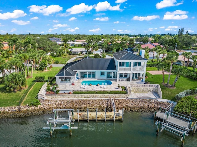 back of house with a water view, a lawn, and a patio