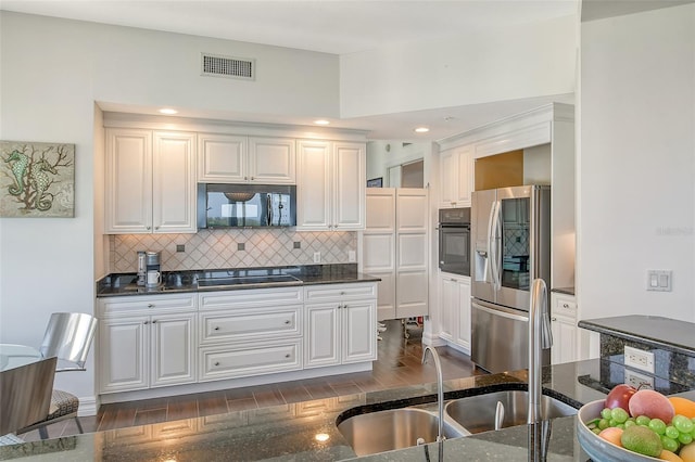 kitchen with decorative backsplash, white cabinets, black appliances, dark wood-type flooring, and sink