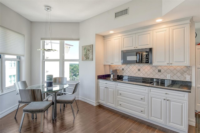 kitchen featuring white cabinets, black appliances, hanging light fixtures, and dark hardwood / wood-style floors