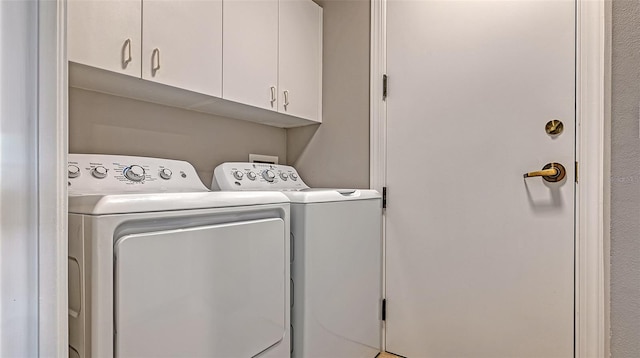 clothes washing area featuring cabinets and washer and clothes dryer