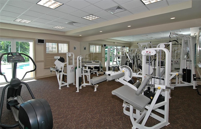 gym featuring a drop ceiling and dark colored carpet