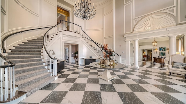 foyer entrance featuring ornamental molding, a high ceiling, and decorative columns