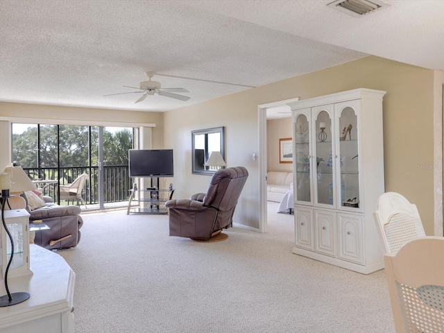 carpeted living room with a textured ceiling and ceiling fan