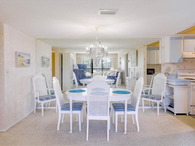 dining space featuring light carpet, a textured ceiling, and a chandelier