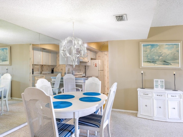 dining room featuring light carpet, a chandelier, a textured ceiling, and sink