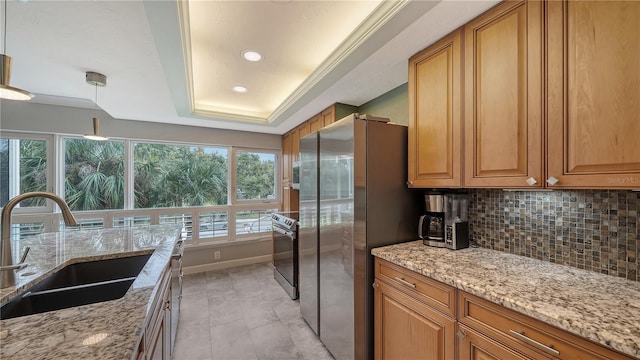 kitchen featuring sink, light stone counters, a raised ceiling, backsplash, and stainless steel appliances