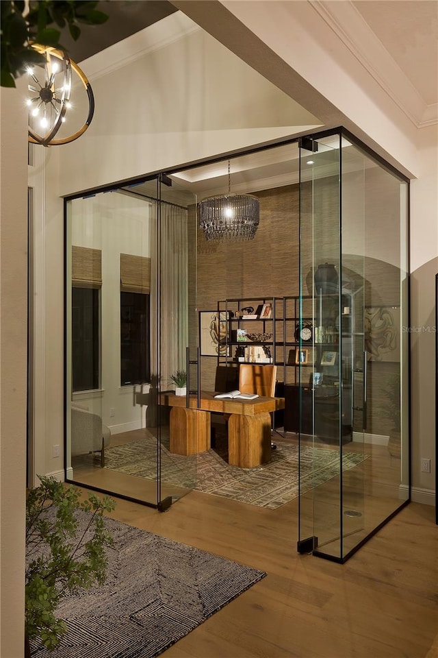 wine room featuring wood-type flooring, ornamental molding, and a chandelier