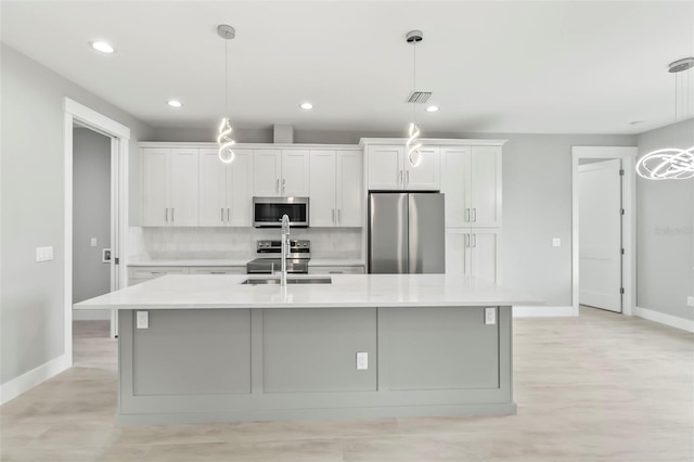 kitchen with decorative light fixtures, backsplash, light wood-type flooring, and stainless steel appliances