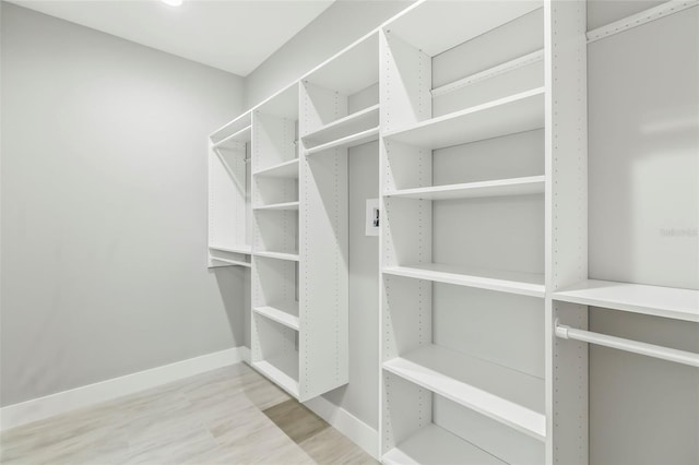 walk in closet with light hardwood / wood-style floors