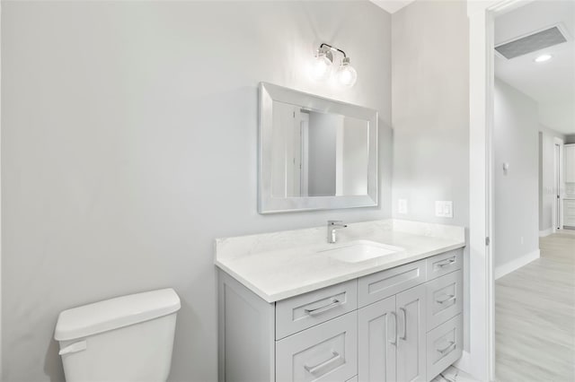 bathroom featuring oversized vanity, toilet, and wood-type flooring