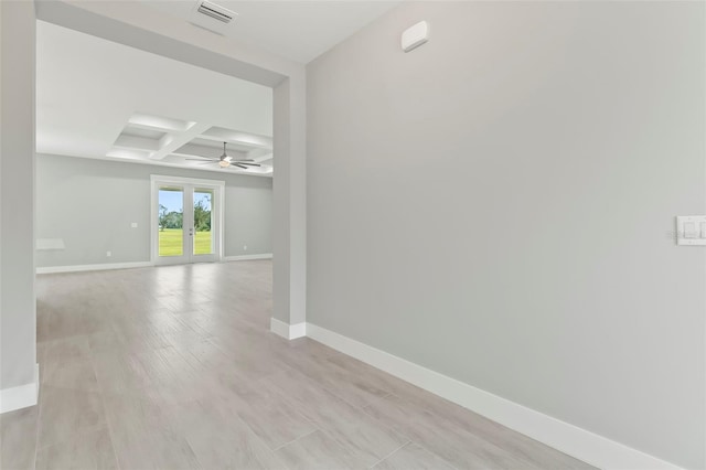 empty room featuring french doors, ceiling fan, light hardwood / wood-style flooring, coffered ceiling, and beam ceiling