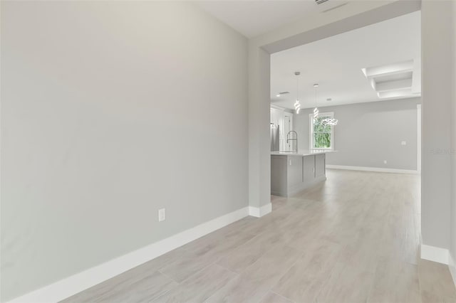 unfurnished room with a chandelier, light hardwood / wood-style floors, and sink