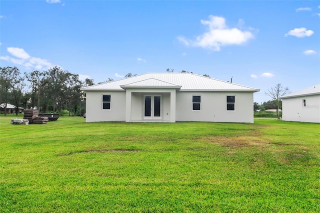 back of property with a lawn and french doors