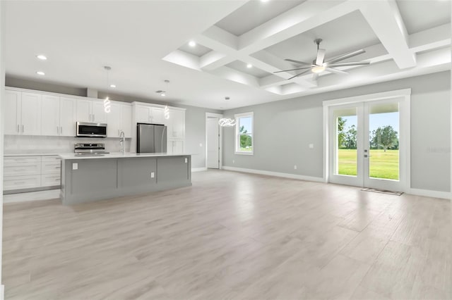 kitchen featuring a center island with sink, coffered ceiling, light hardwood / wood-style floors, and stainless steel appliances