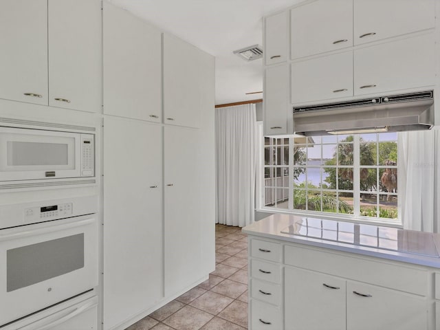 kitchen featuring light tile floors, white appliances, and white cabinetry