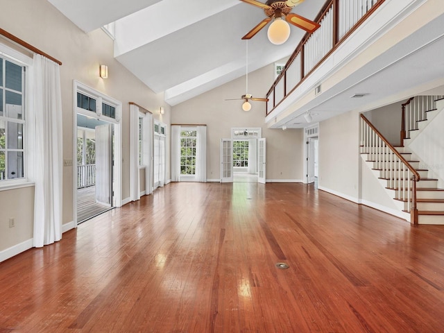 unfurnished living room with a high ceiling, ceiling fan, and dark hardwood / wood-style flooring