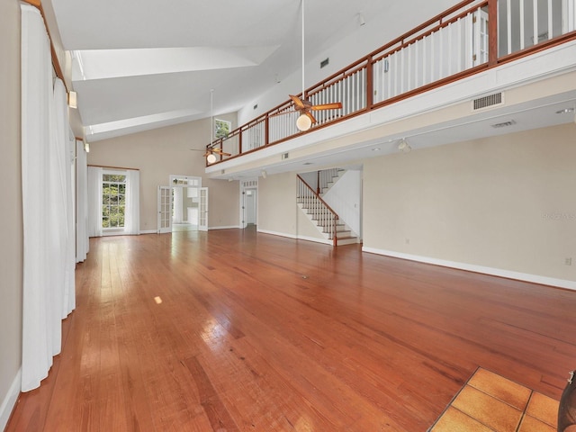 unfurnished living room with high vaulted ceiling and light hardwood / wood-style floors