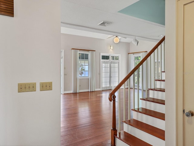 entrance foyer with a textured ceiling, rail lighting, and dark hardwood / wood-style flooring